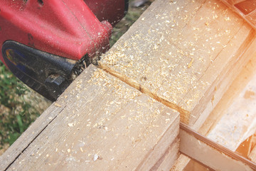 The Builder saws wooden boards, close up