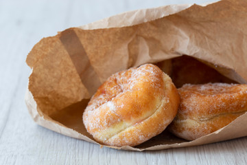 Jam doughnuts in a brown paper bag,  recycling packaging,  on a grey wood background