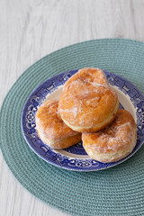 Jam doughnuts on a blue and white plate and green table mat on a grey wood background