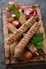 Closeup of grilled chicken kebabs on a rustic wooden serving tray, vertical shot