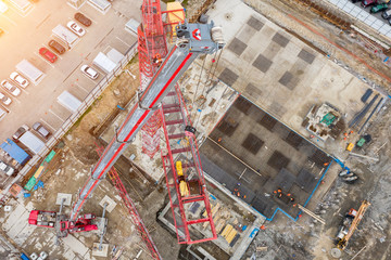 Installation of a construction crane, with the help of a crane on a truck, aerial top view of the pit and building site, the foundation.