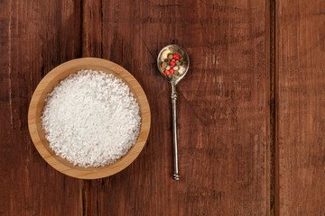 Obraz na płótnie Canvas A bowl of sea salt and a spoon with pepper, shot from above on a dark rustic wooden background with a place for text