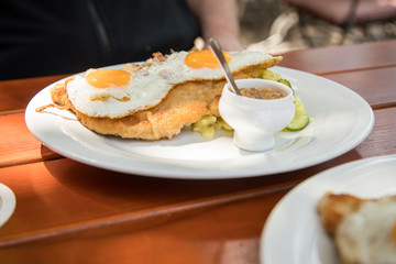 Schweine Fleisch Schnitzel Wiener Art mit Spiegelei als Hamburger dazu Gurken Kartoffelsalat und Bayrischen süßen Senf im Biergarten Restaurant