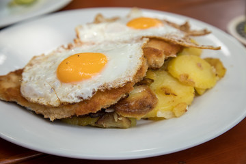 Schweine Fleisch Schnitzel Wiener Art mit Spiegelei als Hamburger dazu Bratkartoffeln im Biergarten Restaurant
