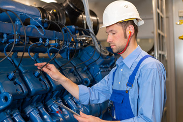  worker with helmet working on big generator