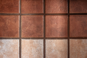 Warm-colored ceramic tiles decorate a wall; one line of lighter color adds visual cadence to the otherwise monotonous design.