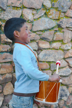 Little native american boy playing traditional sikuri drum.