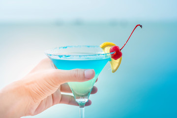 Human hand is holding  summer drink on beach