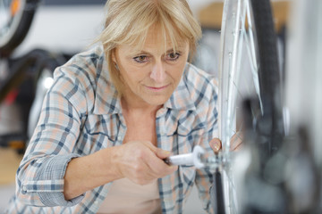 mature woman tightening bicycle wheel