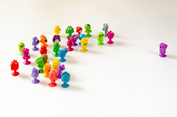 A single character faces a group of figures. Colorful rubber monster figurines on white background. Concept of the conflict between a single and a group