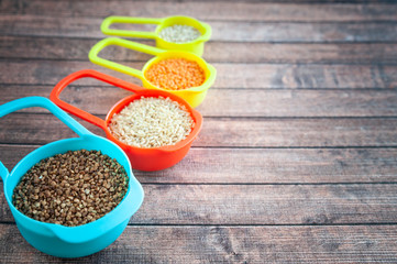 Set of different cereals in multi-colored containers, Oatmeal buckwheat, barley and rice, space for text