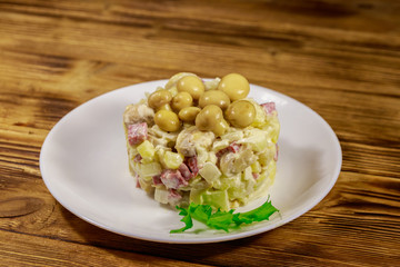 Potato salad with marinated mushrooms, sausage, onion and mayonnaise on wooden table