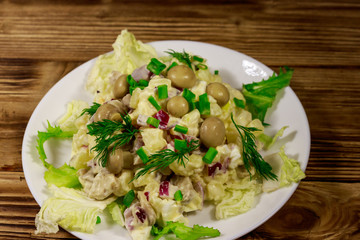 Potato salad with marinated mushrooms, eggs, red onion and mayonnaise on wooden table