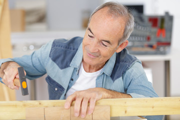 senior man hammering wooden dowels at home