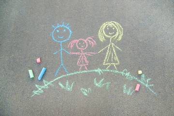 Child draws a family on the pavement with chalk. Selective focus.