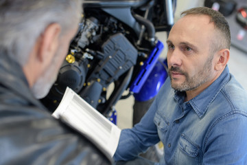 men talking while examining motorbikes