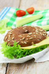 Brown bagel with sunflower seeds with cheese and lettuce, closeup