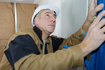 male worker bundling pipework on interior building site