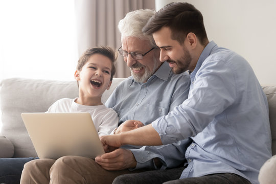 Three generations of men relax at home with laptop