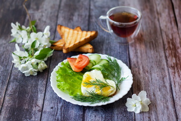 Fried eggs with lettuce, cucumber and tomato slices on wooden background