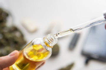 bottle of oil Cannabis in pipette in hand, CBD cannabis OIL on white background, medical marijuana...