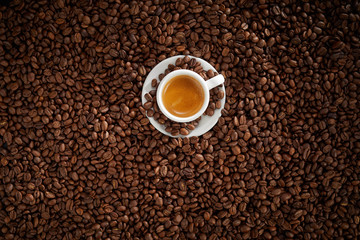 Small white cup of frothy strong espresso coffee