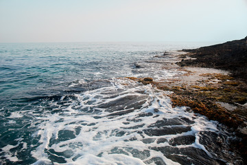 Aerial top view of sea waves hitting rocks on the beach with turquoise sea water. Amazing rock cliff seascape in the coastline. Aerial view of sea waves and fantastic Rocky coast. Mediterranean Sea.