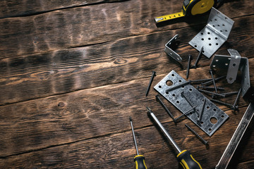 Mounting plates and woodwork tools on a wooden workbench. Construction or carpentry flat lay background with copy space. Under construction concept.