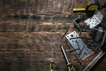 Mounting plates and woodwork tools on a wooden workbench. Construction or carpentry flat lay background with copy space. Under construction concept.