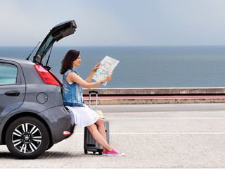Woman traveler on hatchback car on seaside road. - obrazy, fototapety, plakaty