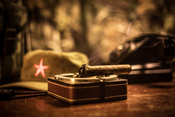 Close up of a Cuban cigar and ashtray on the wooden table. Communist dictator commander table in...