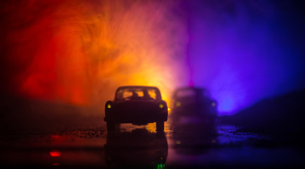 Fototapeta na wymiar Police car chasing a car at night with fog background. 911 Emergency response police car speeding to scene of crime. Selective focus
