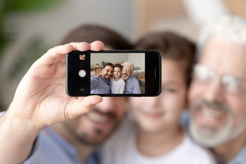 Smiling three generations of men take selfie on smartphone