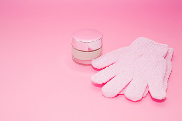 Beauty luxury cosmetic cream container and bath massage gloves on pink background . Beauty background with facial cosmetic products. Package for cream. Beauty and spa concept
