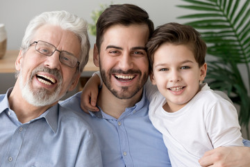 Portrait of three generations of men hug look at camera