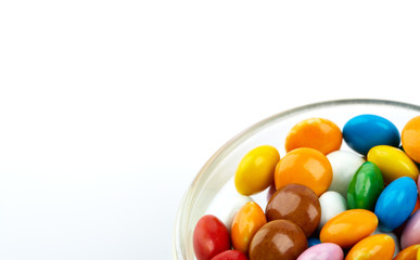 colorful candy on white background. Rainbow sprinkles for topping ice cream and cake. Small candies in colored chocolate glaze.