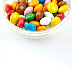colorful candy on white background. Rainbow sprinkles for topping ice cream and cake. Small candies in colored chocolate glaze.