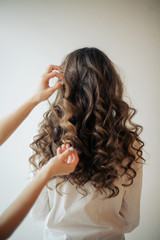 Naklejka premium Closeup of female hands of hairdresser or coiffeur makes hairstyle