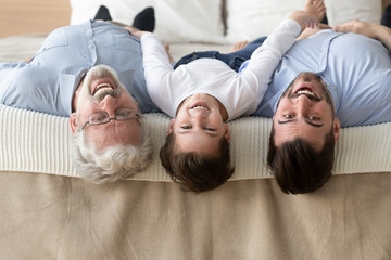 Portrait of three generations of men lying upside down