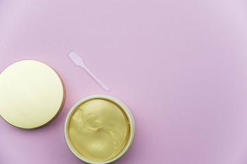 Hydrogel cosmetic eye patch jar with golden patches against dark circles under eyes with spoon. Beauty health care concept. Flat lay set on pink background. 