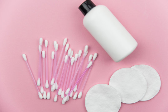 Makeup removal, hygiene, spa and beauty concept. Flat lay with copy space for text. Cotton cosmetic make up removers tampons. Cotton pads, swabs, ear sticks and tonic on trendy pink coral background.