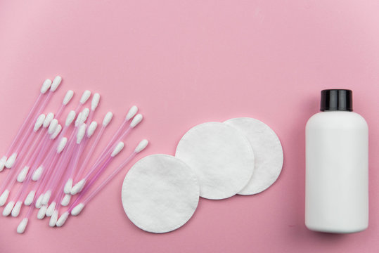 Makeup removal, hygiene, spa and beauty concept. Flat lay with copy space for text. Cotton cosmetic make up removers tampons. Cotton pads, swabs, ear sticks and tonic on trendy pink coral background.