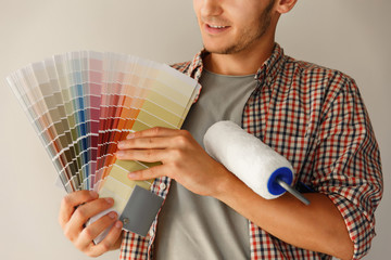 Man holding color palette and paint roller and looking to camera