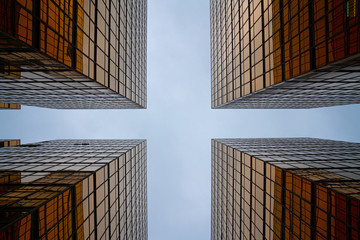 Golden glass building facade in worm eye view in cross view to see the clear sky / abstract architecture / architectural material / background texture