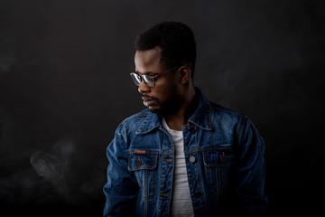 Portrait of african guy in denim jacket in dark - Powered by Adobe