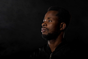 Portrait of handsome young African man on black background