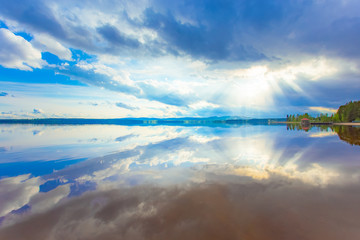 Summer lake landscape with fine reflections and dramatic sky. Sotkamo, Finland.