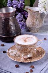 Freshly brewed coffee with a milky foam topped with cinnamon in a brown cup