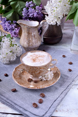 Freshly brewed coffee with a milky foam topped with cinnamon in a brown cup