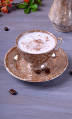Freshly brewed coffee with milky foam topped with cinnamon in a cup against the gray wooden background